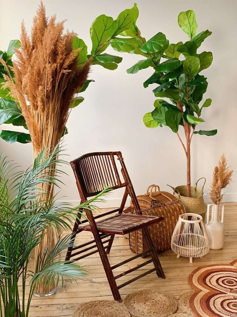 brown chair surrounded by artificial trees and pampas grass - photography props